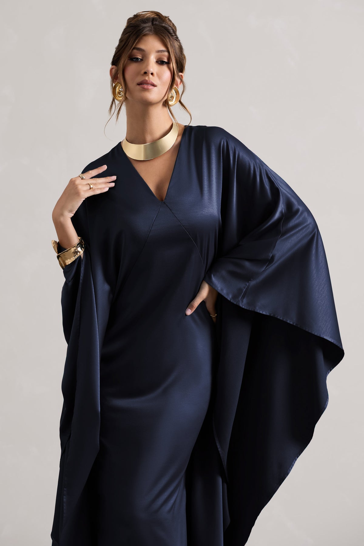Alohi | Navyfarbenes Satin-Maxikleid mit tiefem Ausschnitt und Cape.