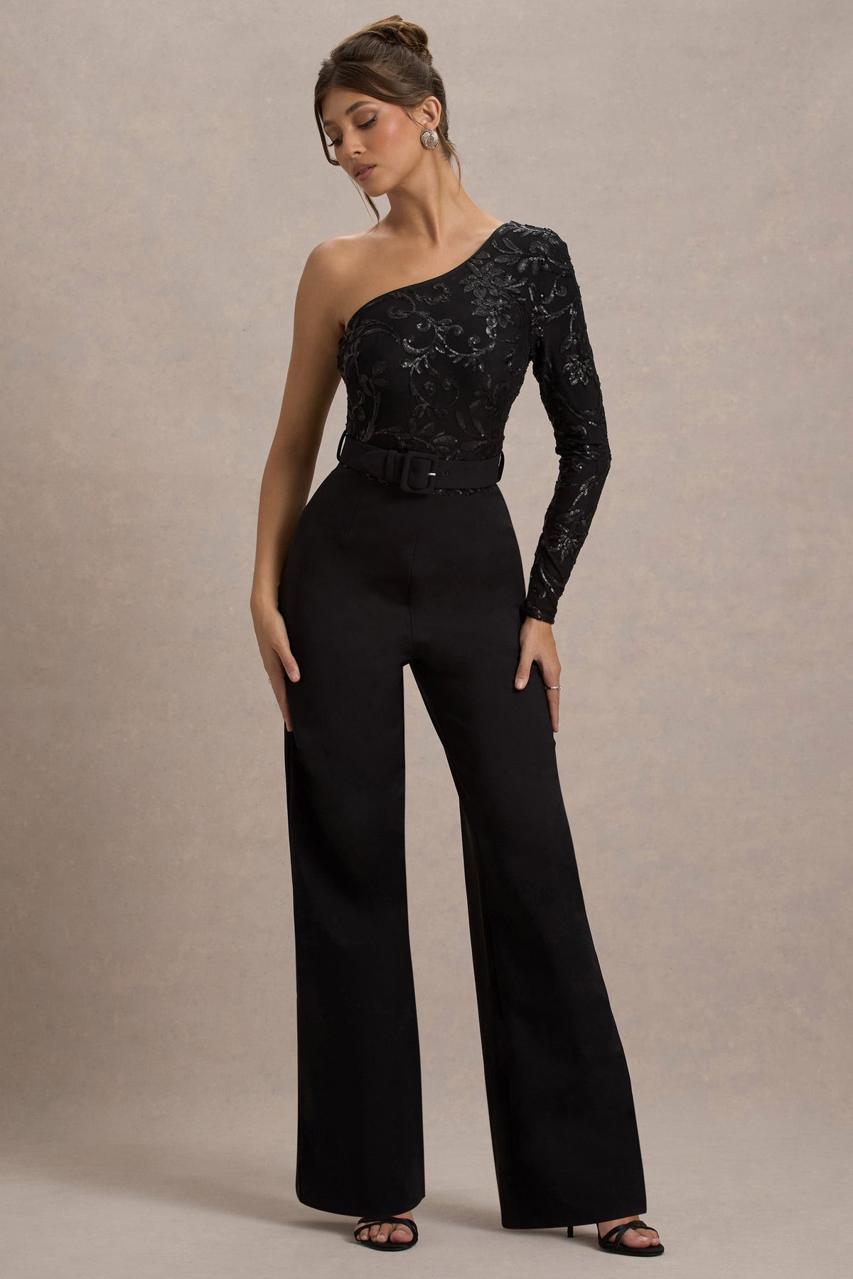 Upgrade | Schwarzer Spitzen-Jumpsuit mit asymmetrischem Schnitt und Gürtel sowie weitem Beinabschluss.