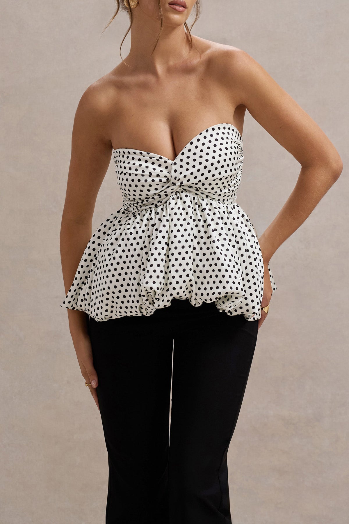 Divina | Weißer und schwarzer Jumpsuit mit Polka-Dots, trägerlos und mit Rüschen.