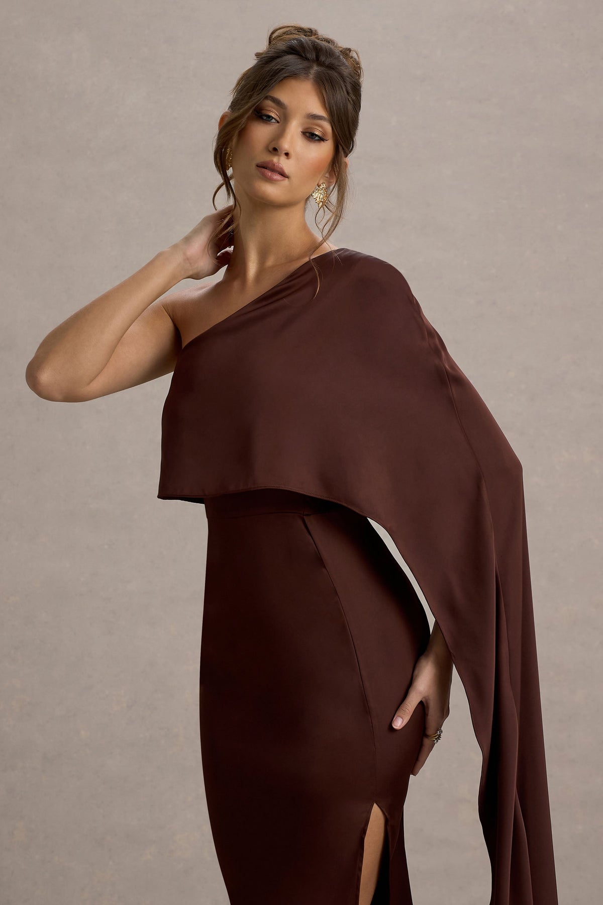 Amora | Braunes Satinkleid mit asymmetrischer Umhang-Ärmel und Schlitz im Maxistil.